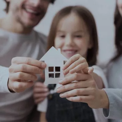 Famille avec projet immobilier tenant une faÃ§ade de maison en papier